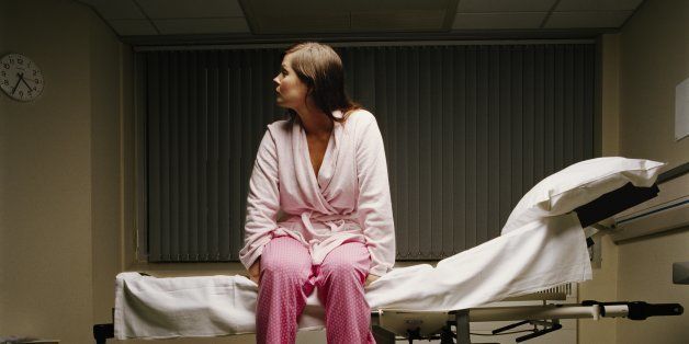 Young female patient sitting on edge of hospital bed