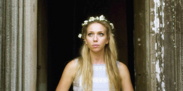 Beautiful, lonely fairytale princess wearing a crown of flowers and looking out the tower window, waiting for her prince.