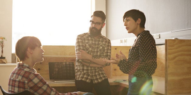 Creative coworkers having casual meeting in office space at sunset