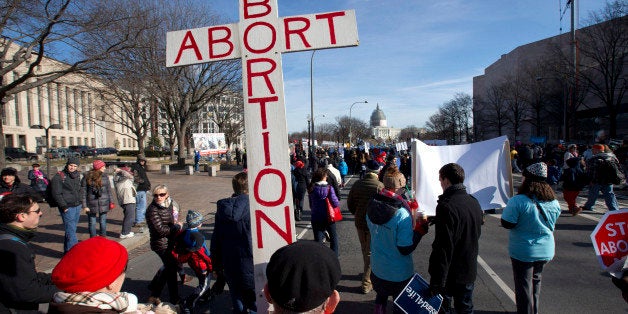 Roy Rohn, 87, of Riverdale, Md., carries a cross that says "abort abortion" as anti-abortion demonstrators march toward the Supreme Court in Washington, Thursday, Jan. 22, 2015, during the annual March for Life on the National Mall. Thousands of anti-abortion demonstrators are gathering in Washington for an annual march to protest the Supreme Court's landmark 1973 decision that declared a constitutional right to abortion. (AP Photo/Jacquelyn Martin)