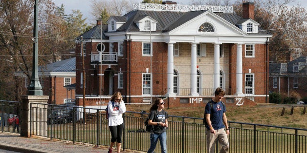 University of Virginia students walk to campus past the Phi Kappa Psi fraternity house at the University of Virginia in Charlottesville, Va., Monday, Nov. 24, 2014. The university has suspended activities at all campus fraternal organizations amid an investigation into a published report in which a student described being sexually assaulted by seven men in 2012 at the Phi Kappa Psi house. (AP Photo/Steve Helber)