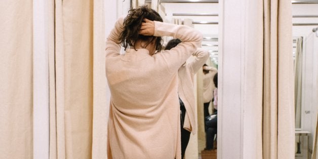 Back view of attractive young woman in front of mirror in changing room.