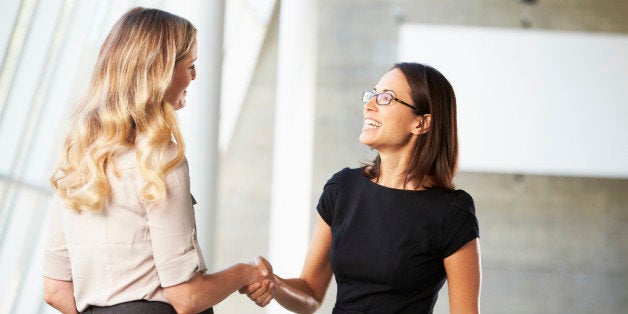 Two Businesswomen Shaking Hands In Modern Office