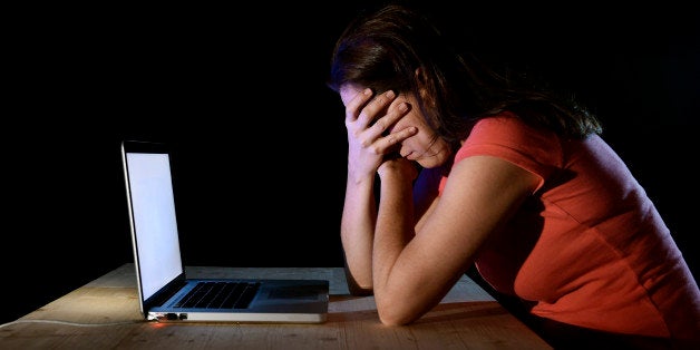 young desperate and depressed freelance worker or student woman working with computer laptop alone late at night in stress suffering internet bullying victim of social network