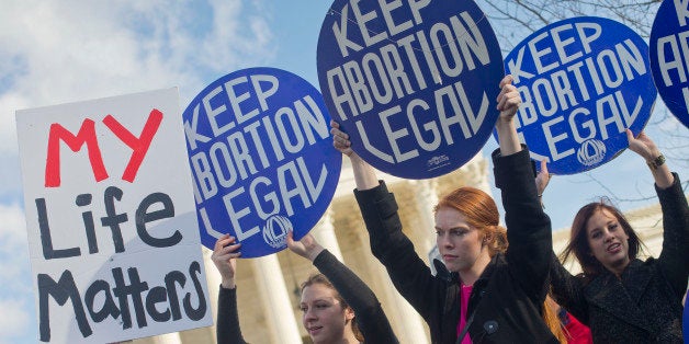 Pro-abortion rights supporters hold up signs in front of the Supreme Court in Washington, Thursday, Jan. 22, 2015, as they wait for the arrival of anti-abortion demonstrators during the annual March for Life. Thousands of anti-abortion demonstrators gathered in Washington for an annual march to protest the Supreme Court's landmark 1973 decision that declared a constitutional right to abortion. (AP Photo/Pablo Martinez Monsivais)