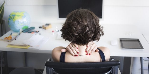 Young woman massaging her neck at desk