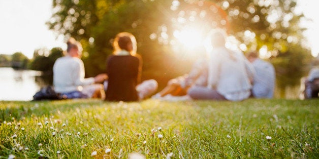 Group of friends sitting at grass on sunny day