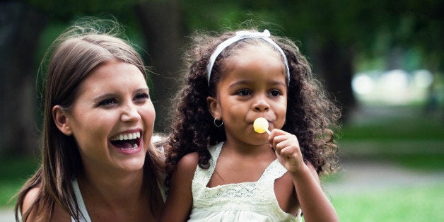 white woman in her 20's playing in the park, with an african american little girl. colorful, high contrast images.