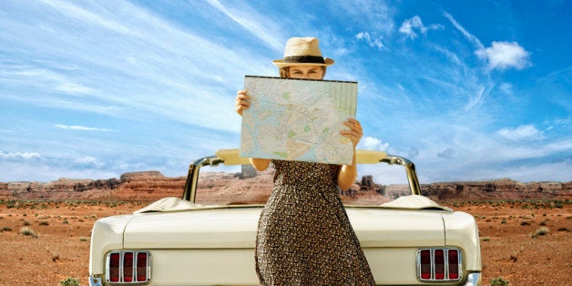 Caucasian woman with convertible reading map on remote road