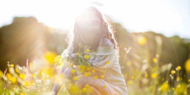 Woman picking flowers in a meadow at sunset, Hampstead Heath, London