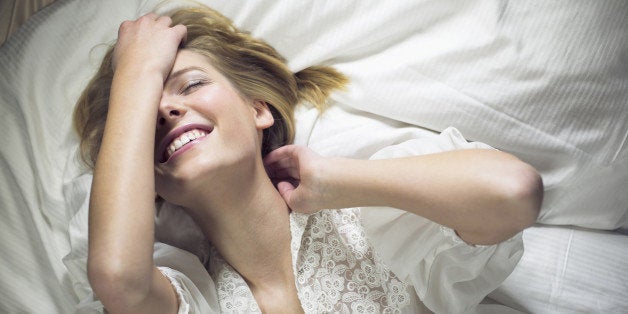 Young woman lying on bed with hand in hair