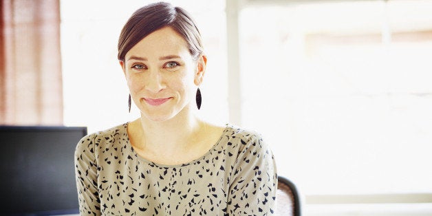 Smiling female businesswoman seated at workstation