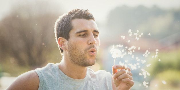 Young man playing with dandelion