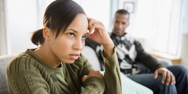 Boyfriend watching frustrated girlfriend on sofa