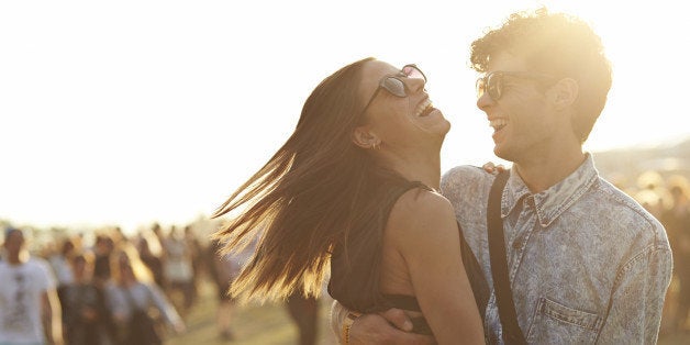 Friends hanging out at big outside music festival, in the sunset.