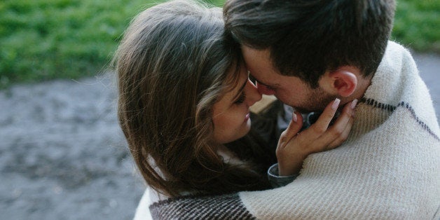 Young couple in love wrapped in plaid standing and looking at each other