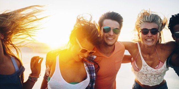 Friends dancing on beach in sunset