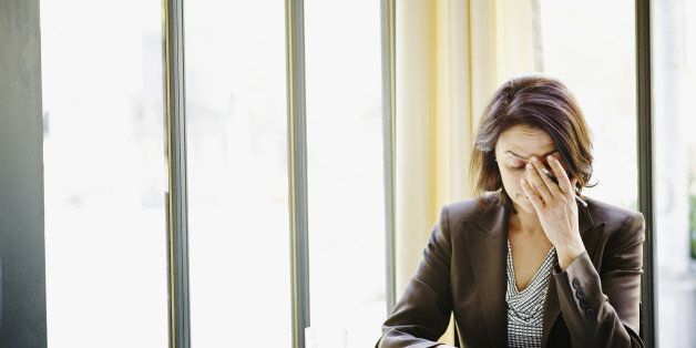 Businesswoman sitting at table in restaurant with head resting on hand