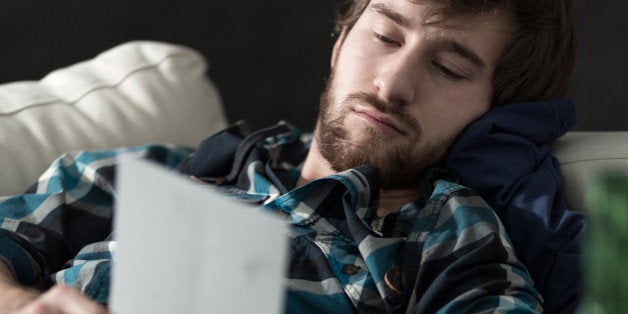 Young sad and depressed man lying on the sofa