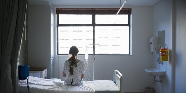 Patient sitting on hospital bed waiting for surgery looking out window