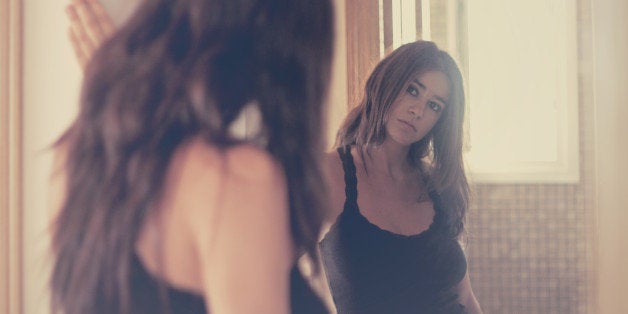 A girl with long hair looking into a mirror.