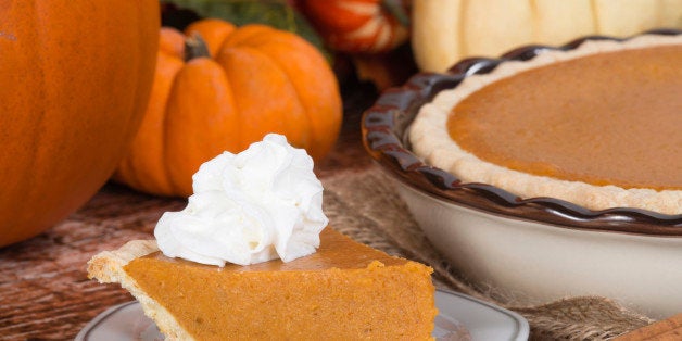 Slice of a pumpkin pie with whipped cream on wooden table. Pie and pumpkins on the background.