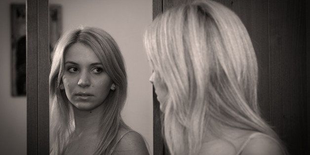 Indoor portrait of a beautiful woman watching in the mirror.