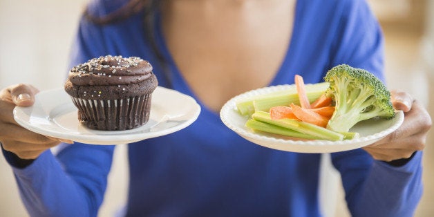 Mixed race woman choosing vegetables or cupcake