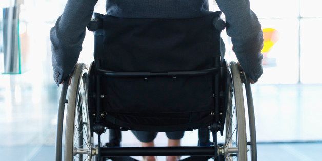 rear view mid section of a businesswoman sitting in a wheelchair in an office