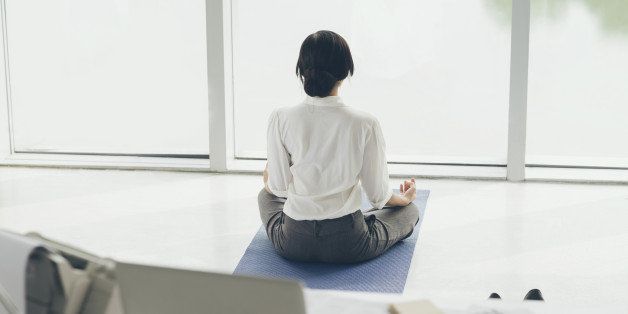 Office worker meditating on the floor, rear view