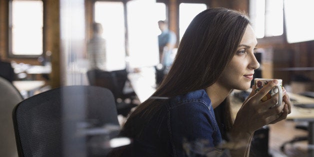 Pensive businesswoman drinking coffee in office