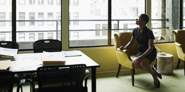 Businesswoman sitting in chair in office looking out window