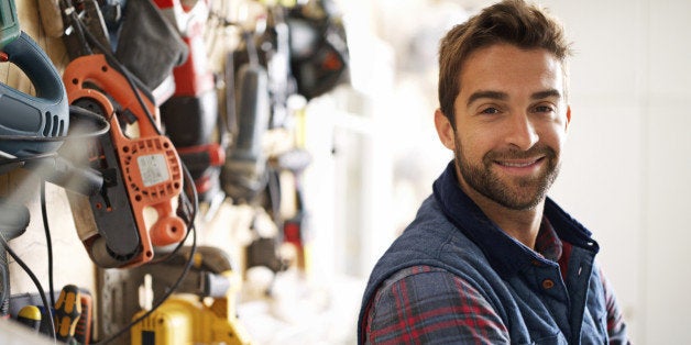 Portrait of a handsome young handyman standing in front of his work tools