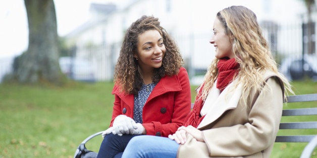 Friends talking on park bench.