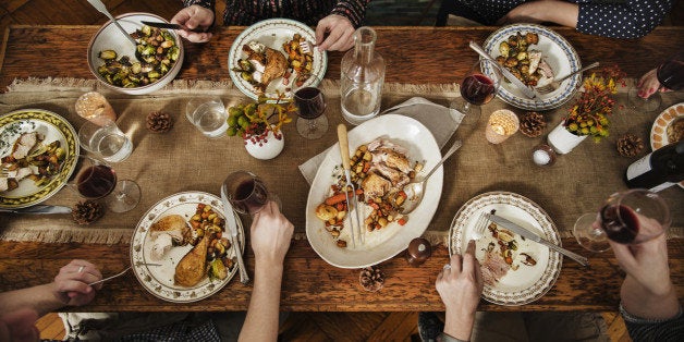 Group of people eating thanksgiving dinner with Turkey, red wine, Brussels sprouts and vegetables