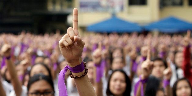 With purple ribbons on their wrists, more than 3,000 students, teachers and nuns from the Catholic-run St. Scholastica's College in Manila, flash the No.1 sign as they dance at their quadrangle to take part in the global campaign to end violence against women and girls dubbed One Billion Rising Friday, Feb. 13, 2015 in Manila, Philippines. (AP Photo/Bullit Marquez)