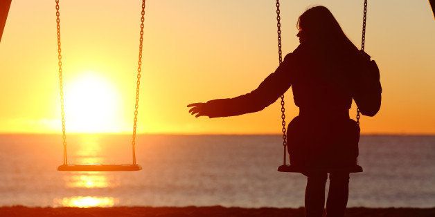 Single or divorced woman alone missing a boyfriend while swinging on the beach at sunset