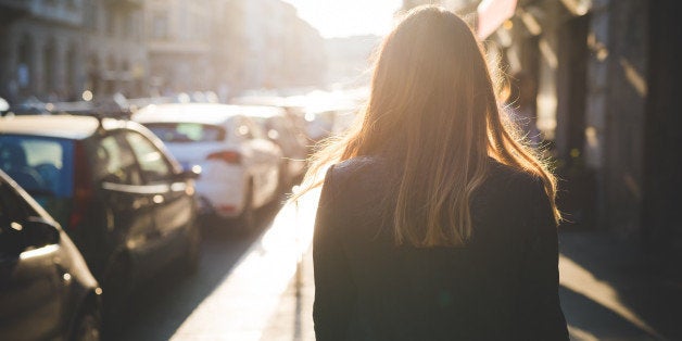 Rear view of young woman strolling on city street