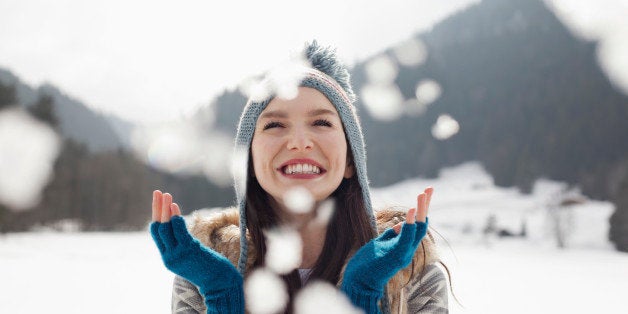 Happy woman enjoying falling snow in field