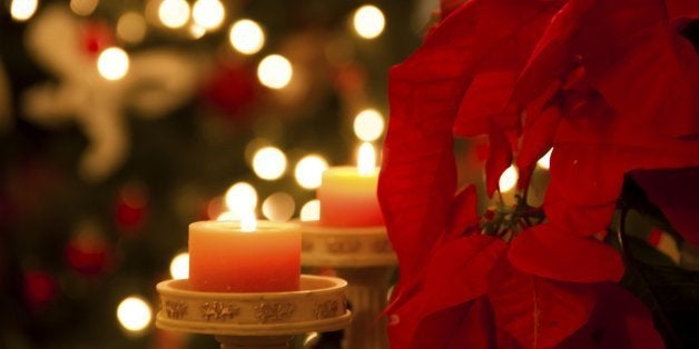 Christmas home decoration with poinsettia flower and candles in foreground and tree lights in background