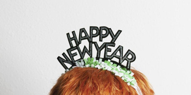 A woman wearing a party tiara with Happy New Year on it, top of head