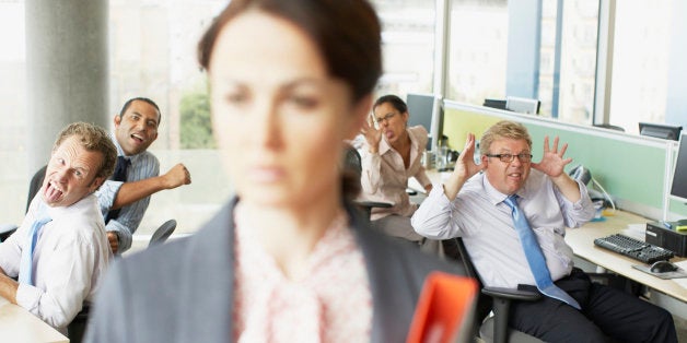 Businesspeople making face at boss in office