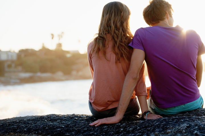 South Africa, Cape Town, Rear view of young couple sitting at beach