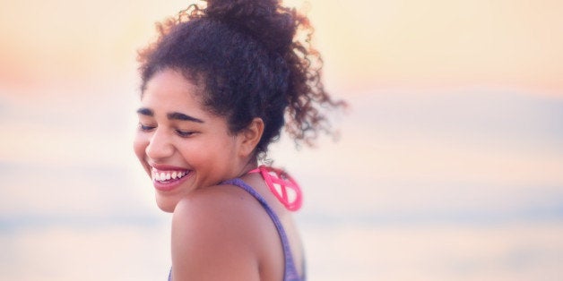 A pretty young woman expressing shy, happy, fun emotions outdoors at the beach.