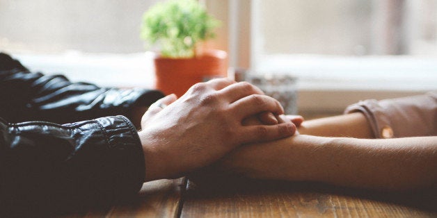 Close up of man and woman's hands holding together in a cafe. Flirting, romanticising, making out concept. Shot with large aperture lens in shallow focus.