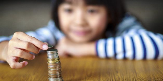Little girl counts his coins on a table, select focus at coins.
