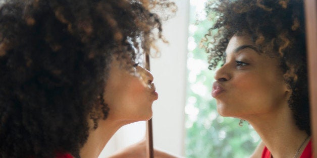 Mixed race woman puckering in mirror