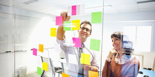 Business people looking at adhesive notes in conference room