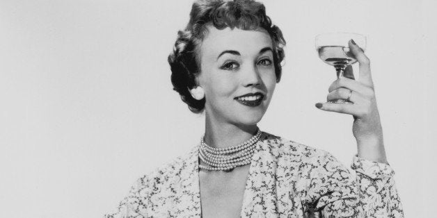 1955: A woman in a matching dress and bolero proposes a toast. (Photo by Chaloner Woods/Getty Images)