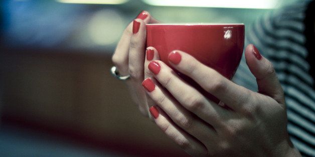 Girl holds red coffee cup.